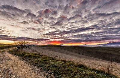 Scenic view of landscape against dramatic sky during sunset