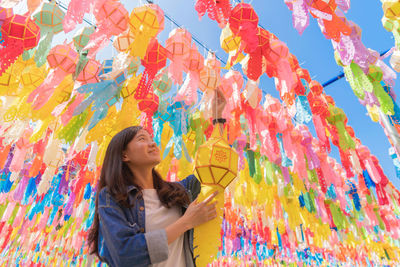 Smiling woman standing against multi colored paper lanterns