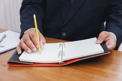 Midsection of man reading book on table