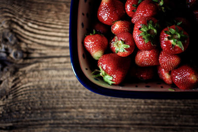 Directly above shot of strawberries in bowl on wooden table