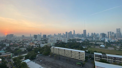 High angle view of modern buildings in city against sky during sunset