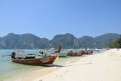 Boats moored on beach against clear sky