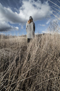 Rear view of woman standing on field against sky