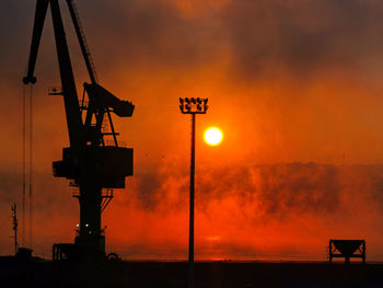 Silhouette of crane against orange sky