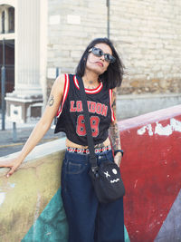 Portrait of young woman standing against building