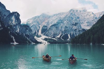 People on lake against mountains