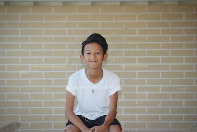 Portrait of a boy standing against brick wall