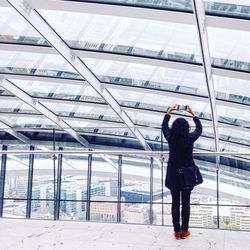 Rear view of woman holding smart phone at railing