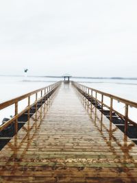 Pier leading towards gazebo amidst sea against sky