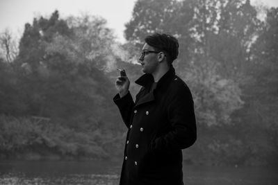 Young man smoking by lake