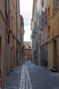 Alley amidst street in city against sky