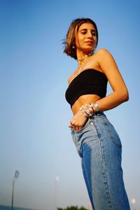 Portrait of woman standing against clear blue sky