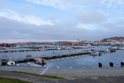Boats in harbor against cloudy sky