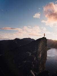 Man standing on rock against sky