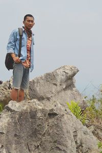 Man standing on rock against sky