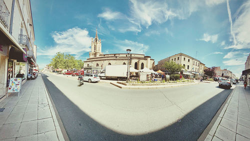 Road amidst buildings in city against sky