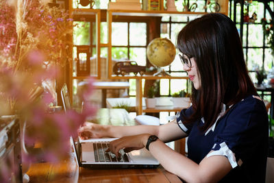 Side view of woman using laptop at table