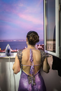 Rear view of young woman looking through window
