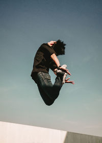 Low angle view of woman jumping against sky