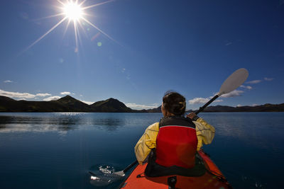 Woman rowing sea kayak on still lake in central iceland