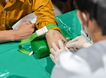 A nurse is putting a green strap on the patient's arm to make the veins convex. 