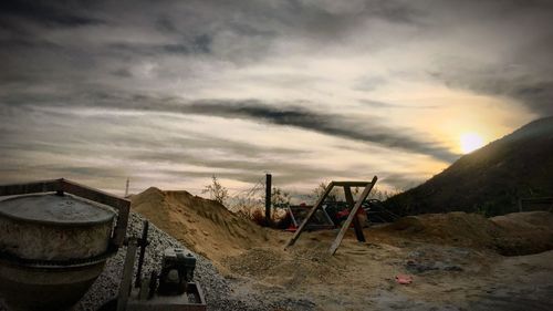 Deck chairs on sand against sky