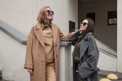 Two girlfriends in matching spring autumn  clothes standing and taking outside in urban background