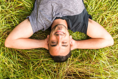 Directly above portrait of handsome young man lying on grassy field