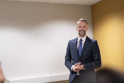 Portrait of businessman standing against wall