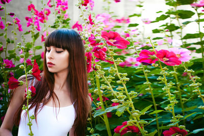 Beautiful woman standing amidst pink flowers at park