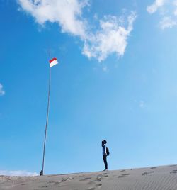 Man standing at beach against blue sky