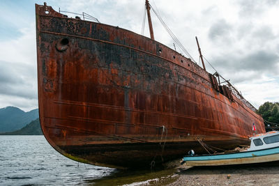 Abandoned boat moored at sea against sky