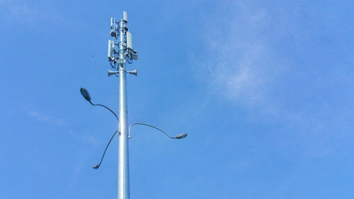 Low angle view of telephone pole against clear blue sky