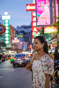 Portrait of smiling young woman standing in city