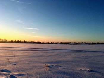 Scenic view of snow covered field against sky at sunset