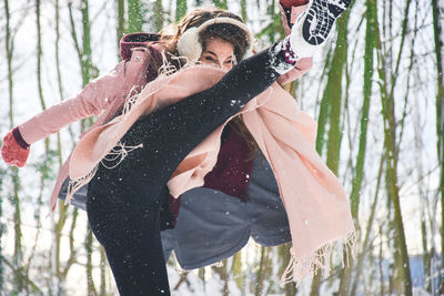 Woman kicking against trees during winter