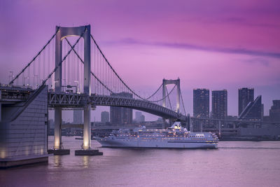 Venus cruise ship sailing in odaiba bay under the rainbow bridge in a pink sunset light.