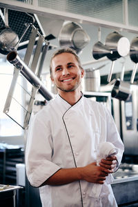 Smiling young chef holding napkin in commercial kitchen