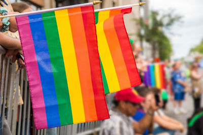 Close-up of rainbow flags with crowd in background during parade