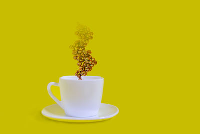 Close-up of coffee cup against yellow background