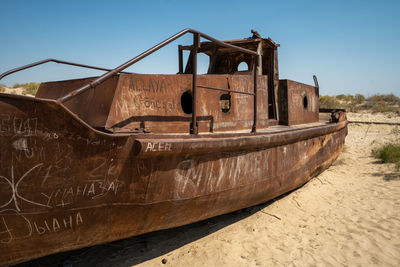 Abandoned boat moored on shore against sky