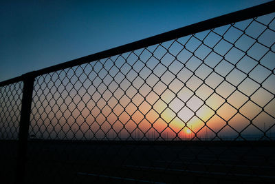 Chainlink fence against clear sky during sunset