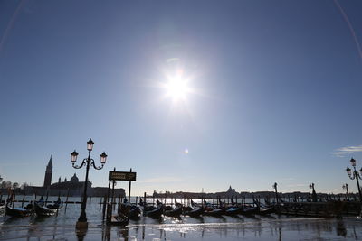 Sailboats moored in canal against sky