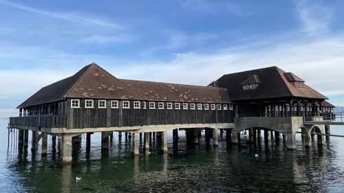 House by lake against sky