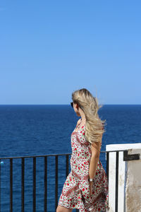 Woman looking at sea against clear sky