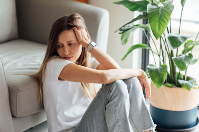 Depressed woman sitting by couch at home