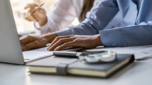 Midsection of man using laptop on table