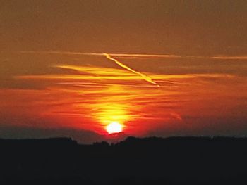 Scenic view of vapor trails in sky during sunset