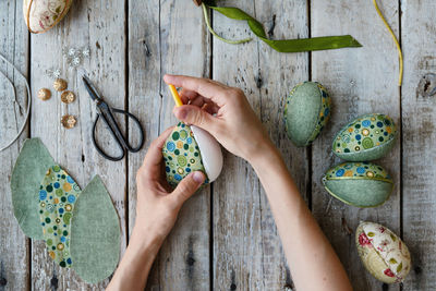 Cropped hand of woman holding christmas decorations on table