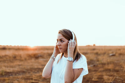 Young woman standing on field against clear sky